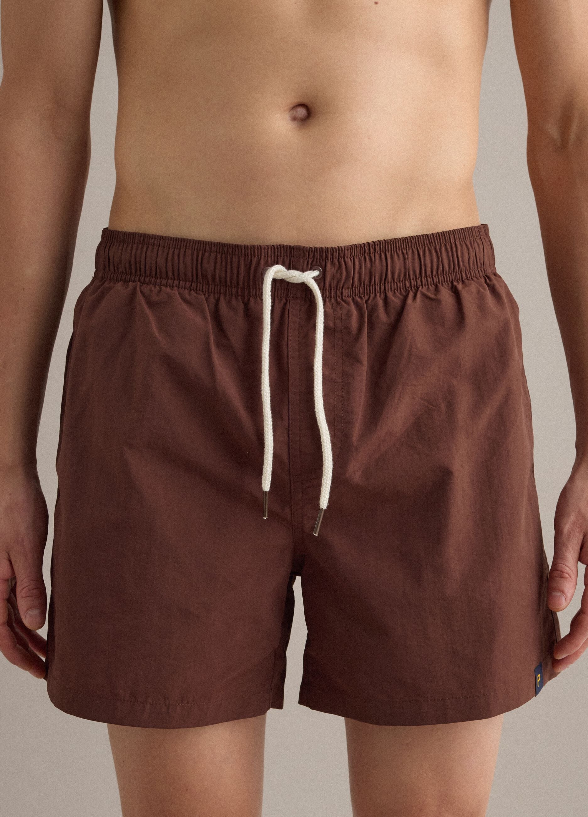 Brown swim shorts with elasticated waistband and drawstring