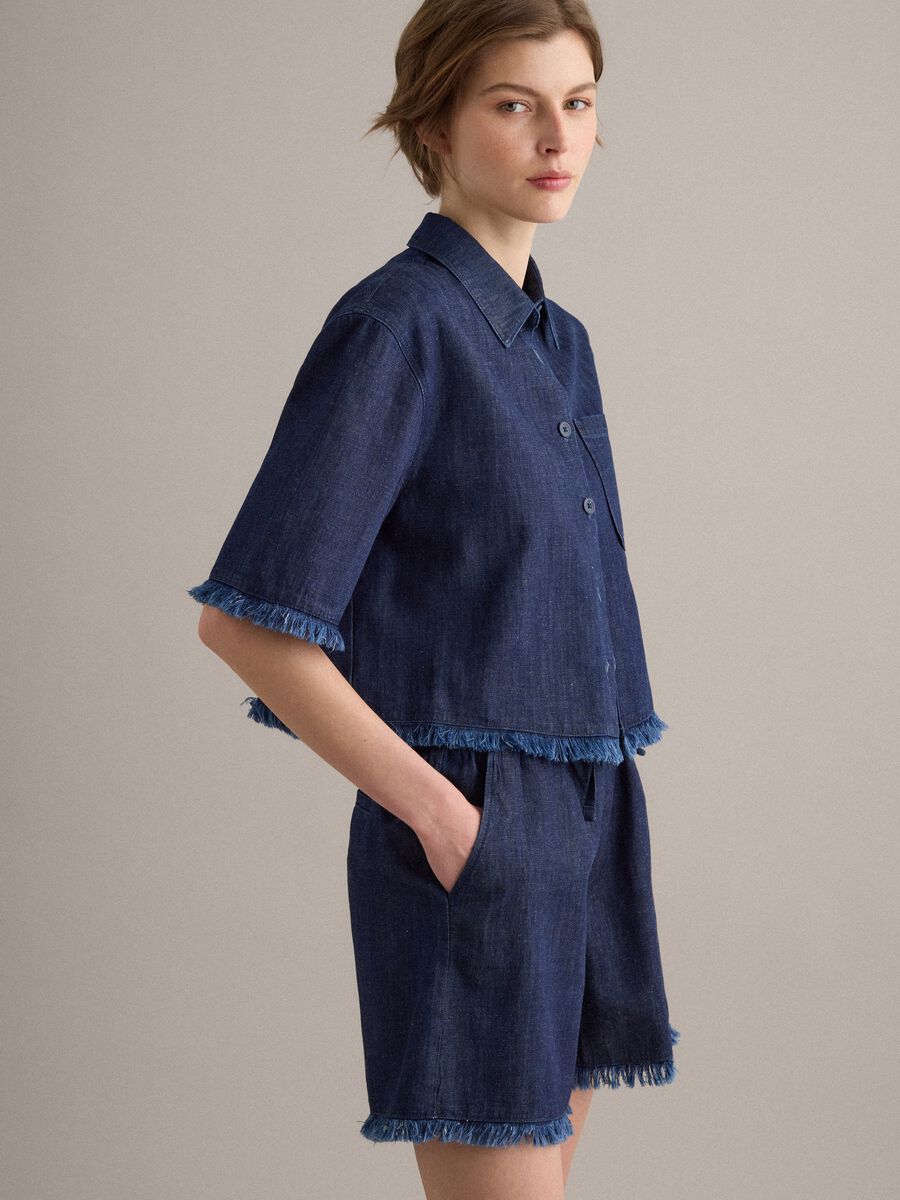 Camicia denim blu in misto cotone oversize fit con bordo sfrangiato_1