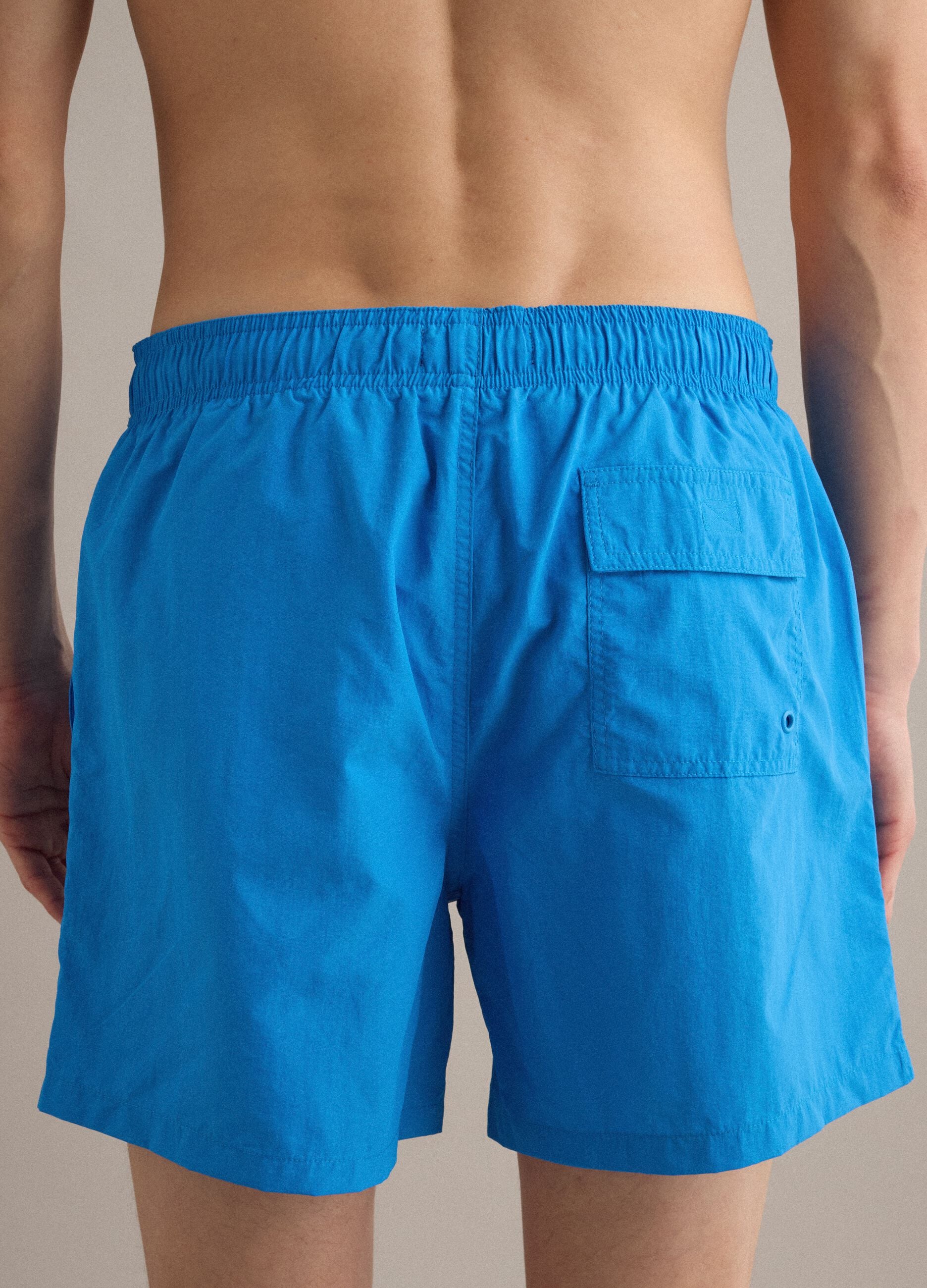 Blue swim shorts with elasticated waistband and contrast drawstring