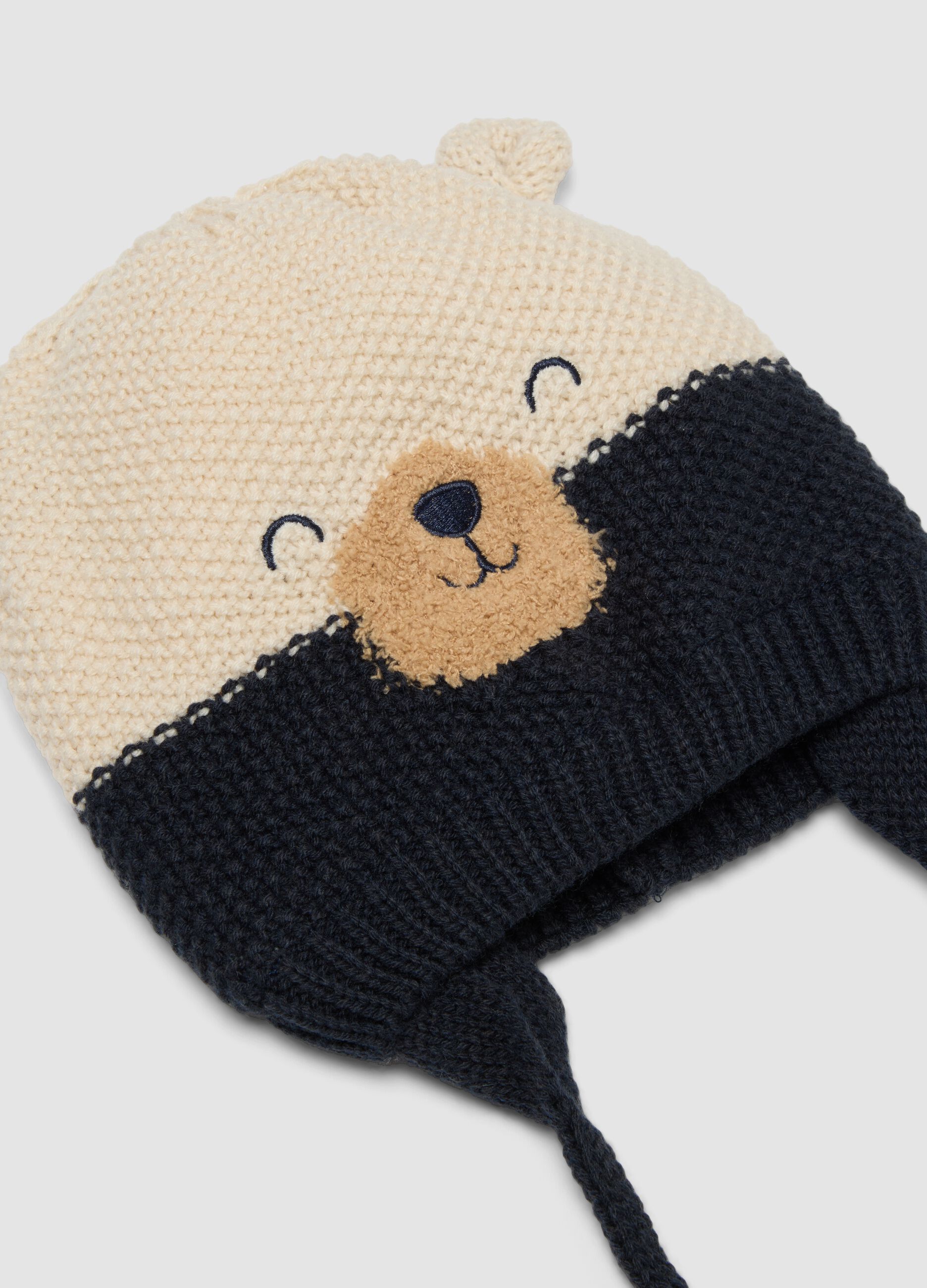 Blue knitted hat with teddy bear motif and ties