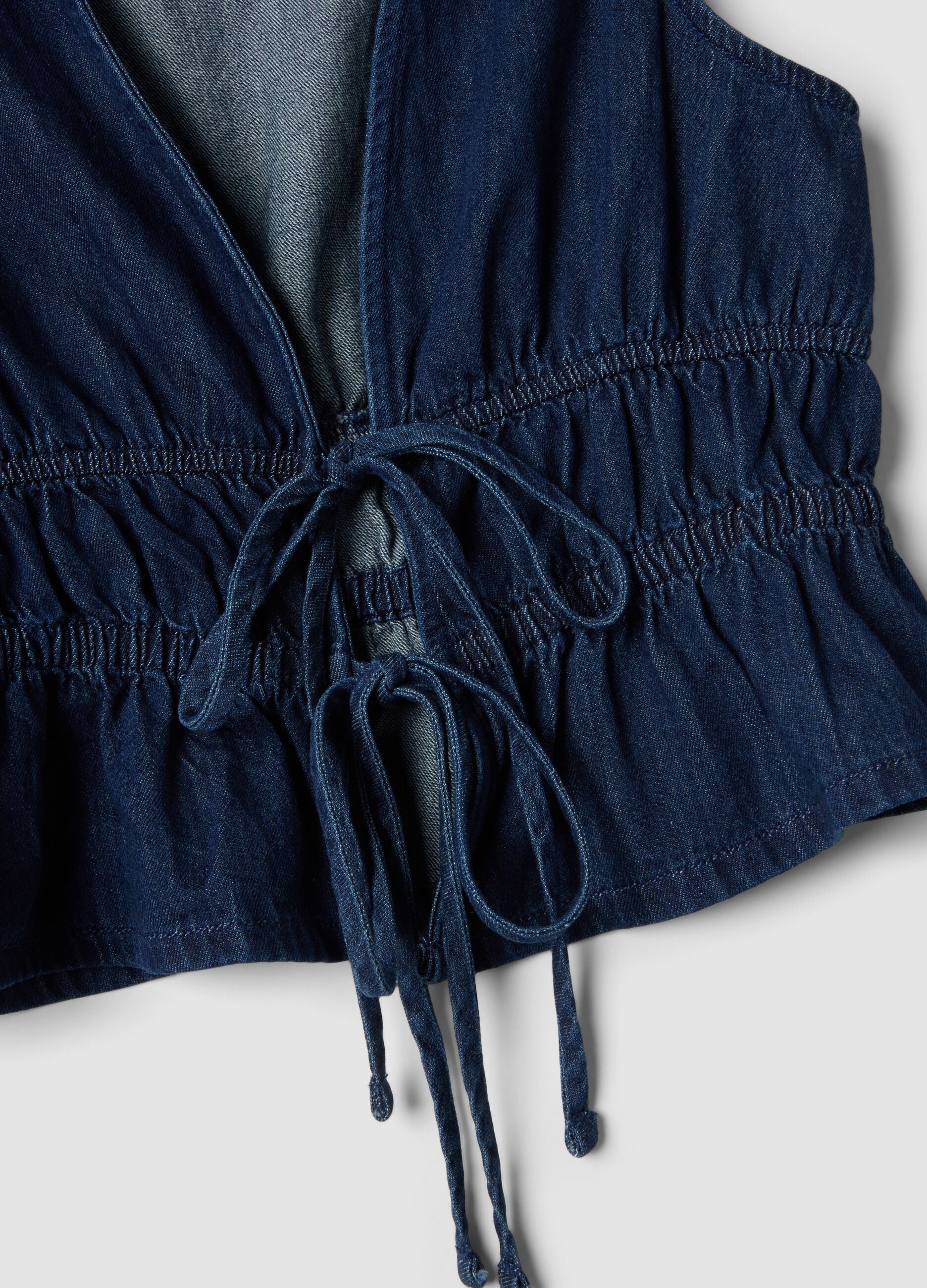 Blue sleeveless denim blouse in pure cotton, slim fit with tie fastening